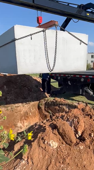 Crane lifting storm shelter at job site in Spur TX